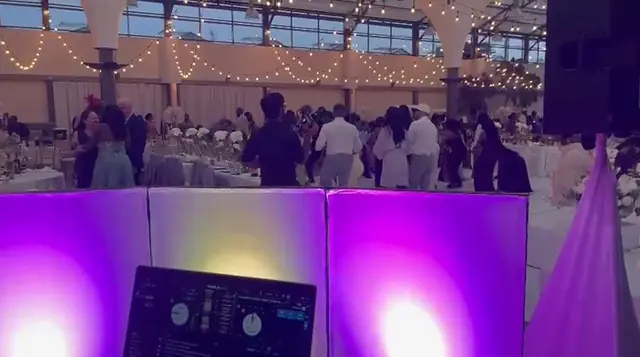 View from behind Rubicon's purple-lit DJ booth across a full wedding reception