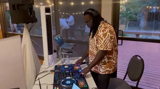 Rubicon's DJ mixing at a party beside a window
