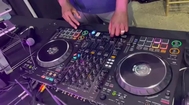 Close-up of hands on the DJ controller pads and jog wheels