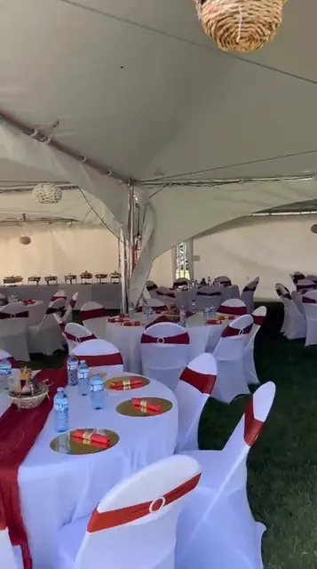 Tented reception with white chair covers, red table runners and gold chargers
