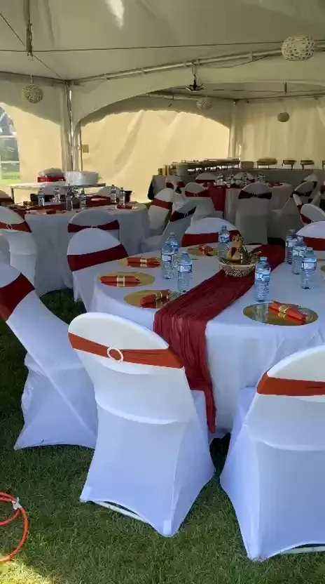 Tented reception with white chair covers, red sashes and gold chargers