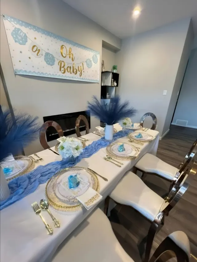 A baby shower room with an Oh Baby banner and a blue table runner
