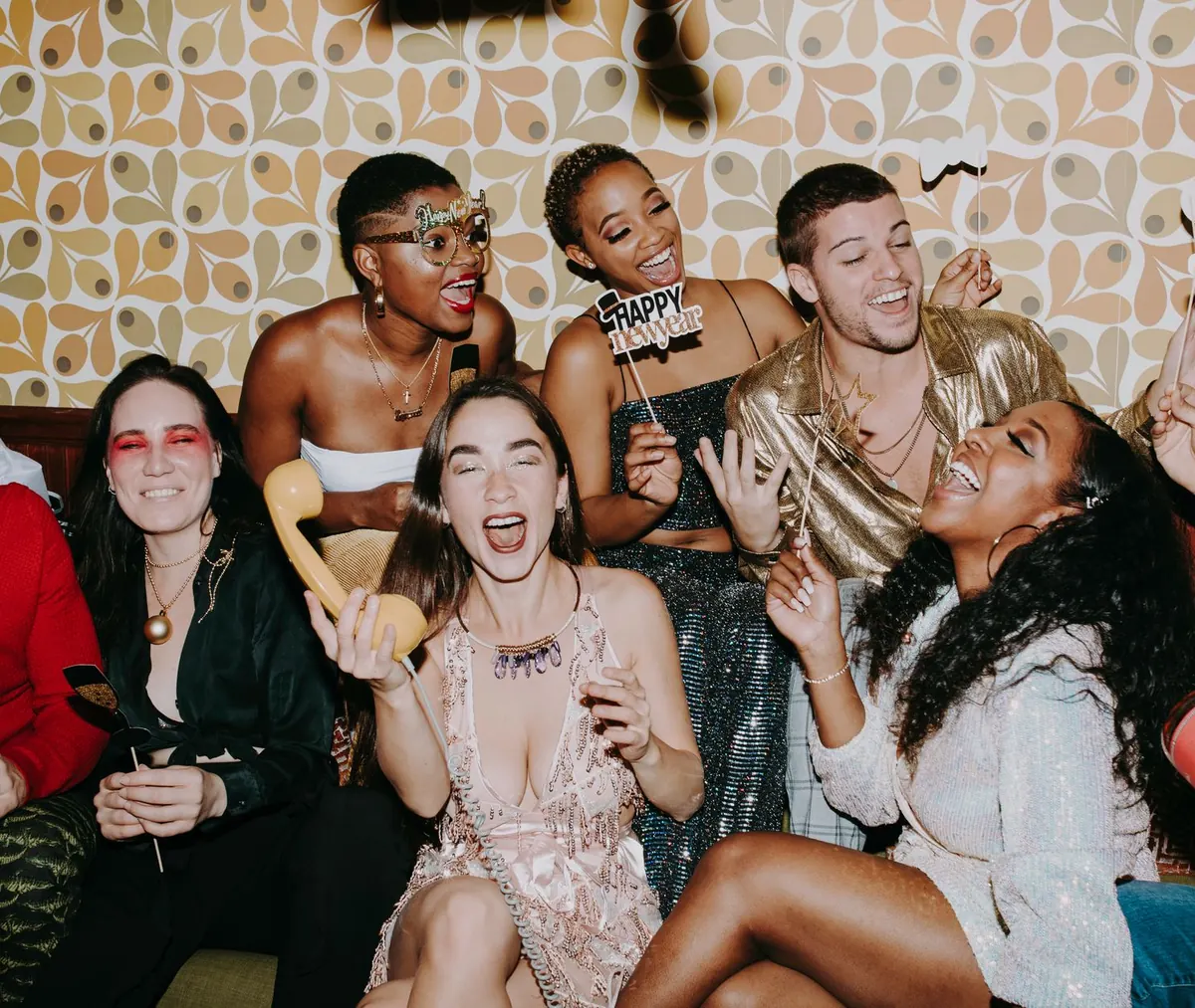 Friends laughing and posing with photo booth props at a party